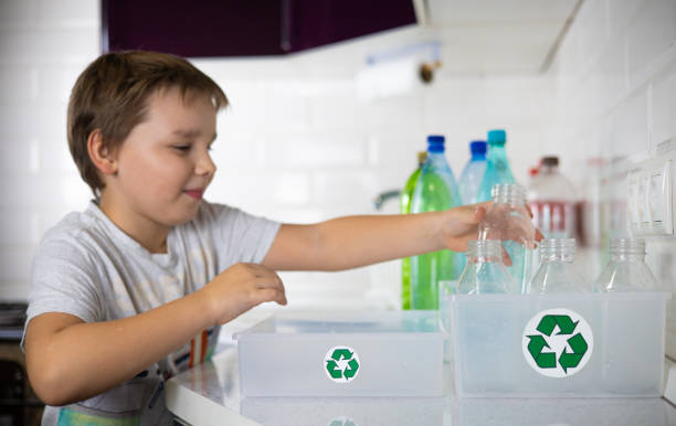 istock A child participates in sorting plastic in the kitchen to be sent for recycling. Cute boy child putting a plastic bottle in a box with a recycle label. Zero waste concept. 2150261116