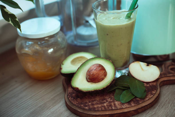 Preparation of healthy smoothie at home. Avocado, apple, spinach, honey. Self-care. Health and wellbeing.