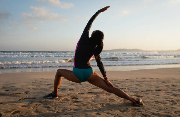 istock Woman surfer warming up on sunset beach 2150263016