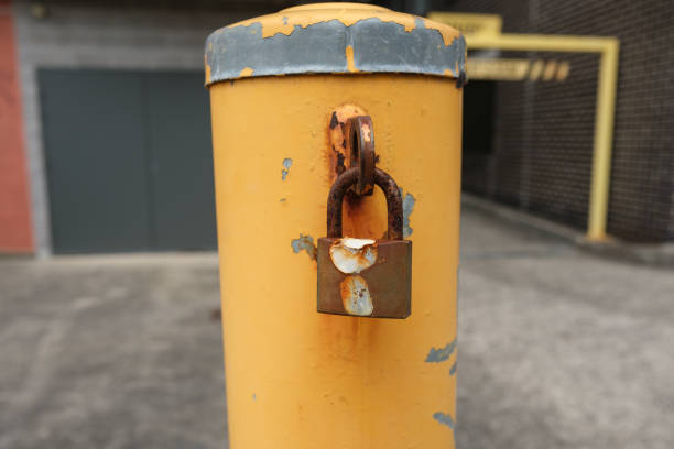 istock Old rusting metal padlock on a yellow metal bollard 2150263052