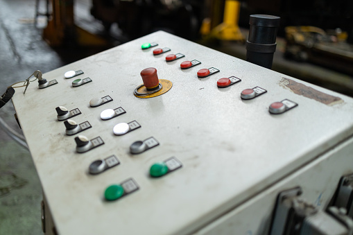 Close-up of an industrial control panel with various buttons and switches in a railway maintenance workshop.