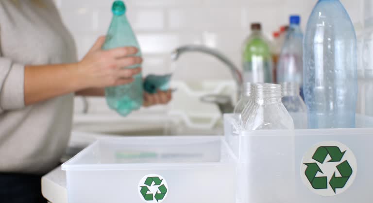 A woman sorts plastic by cutting off labels from bottles and putting them into boxes for recycling. A woman separates plastic depending on its type. Plastic recycling, lifestyle, ecology.