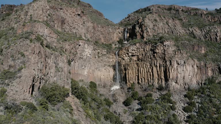 Wide drone shot of a rare waterfall trickling down the side of Oak Creek Canyon, Arizona.