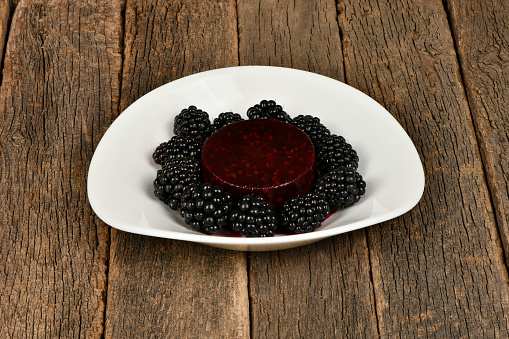 Frozen blackberry smoothies and fresh blackberries on white plate on wooden background. Side view. High resolution photo. Full depth of field.