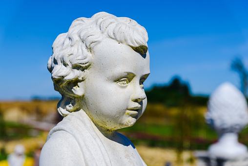 Closeup of a ancient young boy statue at summer park.Close-up.