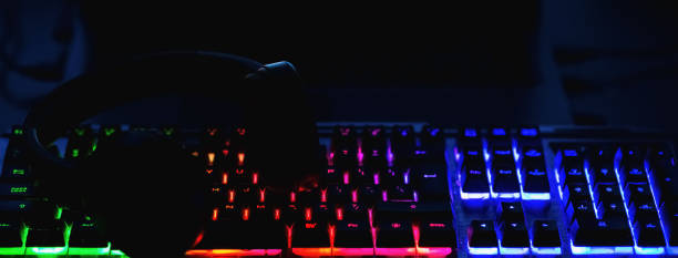 istock Pro gaming illuminated desk, headset, keyboard, computer neon lights. Cyber sport equipment laying on desktop, ready for online video gaming.Dark shot.Banner,advertisement. 2150268346