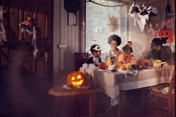 Happy black family talking on Halloween party at dining table.