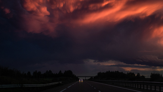 A car is chased by a storm at the sunset in France.