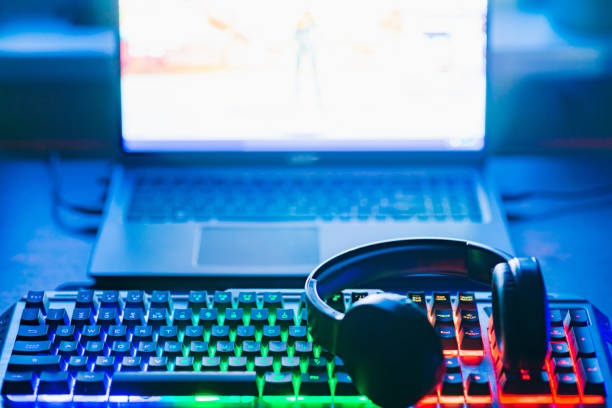 istock Pro gaming illuminated desk, headset, keyboard, computer neon lights. Cyber sport equipment laying on desktop, ready for online video gaming.Dark shot. 2150271478