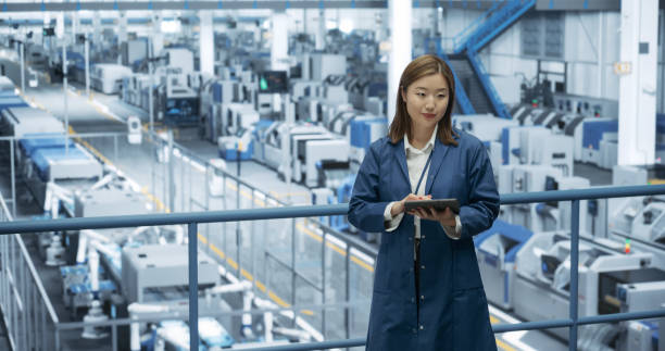 istock Thoughtful Asian Engineer Monitoring and Analyzing Conditions at a Pristine Modern Electronics Factory with Automated Robot Hands Working with the Help of Artificial Intelligence Software 2150271899