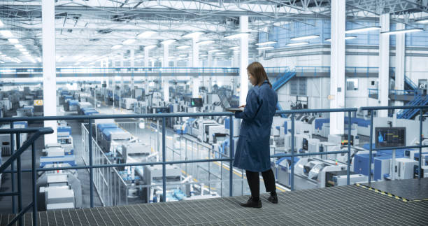 istock Thoughtful Asian Engineer Monitoring and Analyzing Conditions at a Pristine Modern Electronics Factory with Automated Robot Hands Working with the Help of Artificial Intelligence Software 2150271945