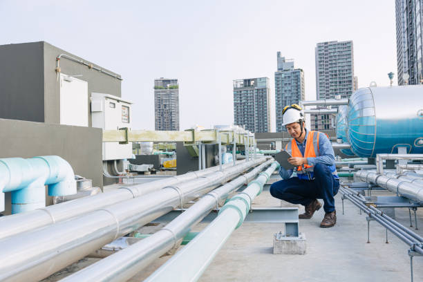 istock engineer male technician worker working service hotel boiler tank hot water supply pipe system. man safety checking maintenance pipeline heating water delivery line at roof top outdoor. 2150272843