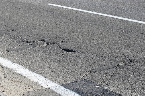 Old asphalt road with dangerously damaged asphalt that has potholes dangerous for the transit of motor vehicles.