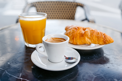 Espresso, orange juice and a French croissant in a sidewalk café in Paris in France.