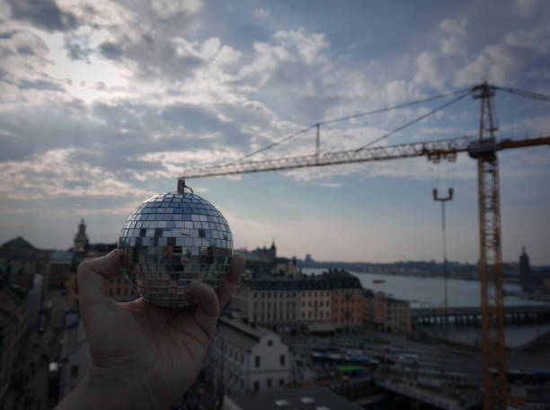 Cropped hand holding a disco ball at a construction crane