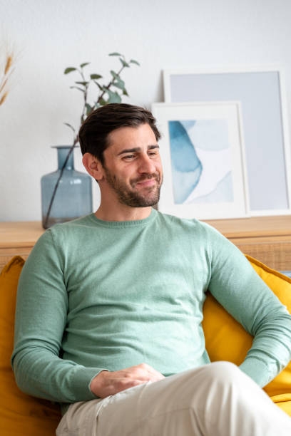 istock Smiling man relaxing on yellow couch 2150275106