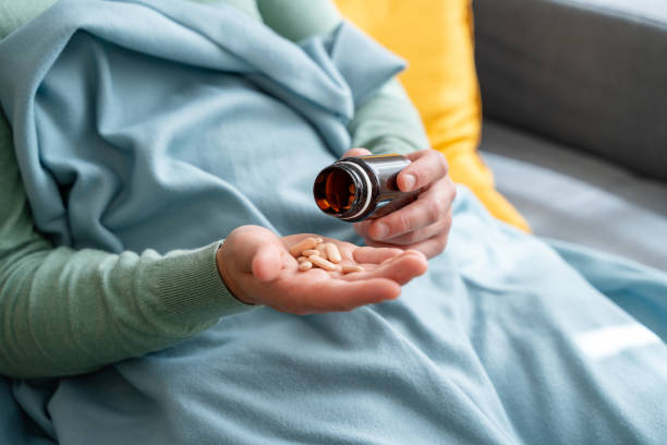 istock Person pouring pills into hand from bottle while covered with blanket 2150275483