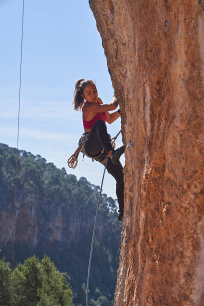 istock Woman climbing sheer cliff using special equipment 2150275839