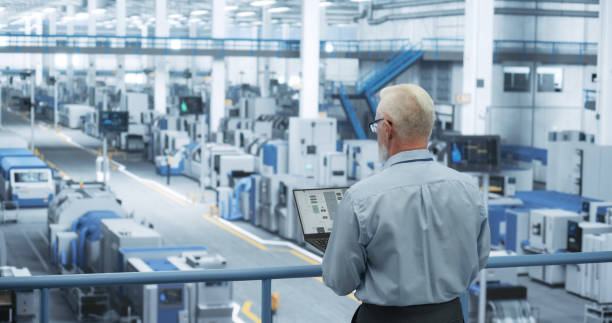 istock Portrait of an Adult Engineer Standing on a Platform, Using Laptop Computer at an Electronics Factory. Technician Making Technical Upgrades Online Over an Internet Software 2150276636