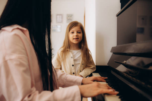 istock Small girl learning play piano with teacher 2150280446