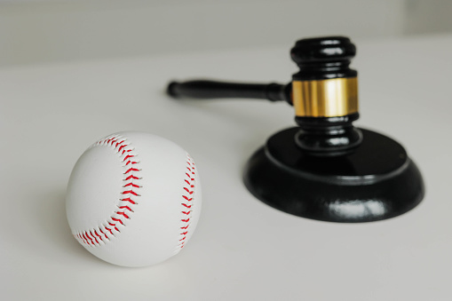 Baseball ball and judge gavel on the table. Scandals in baseball.