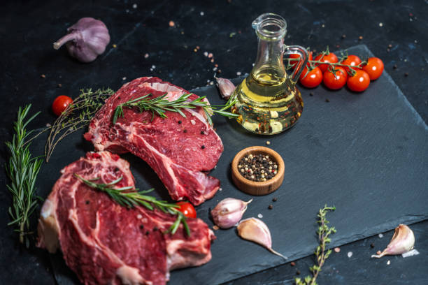 istock Two raw beef steaks on the bone on a black slate serving plate, decorated with ingredients and spices. 2150282071