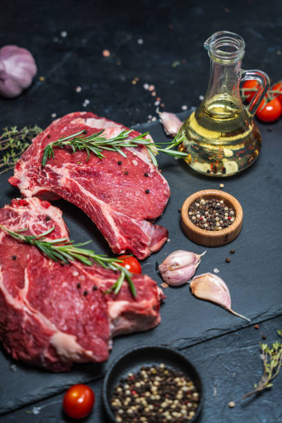 istock Two raw beef steaks on the bone on a black slate serving plate, decorated with ingredients and spices. 2150282103