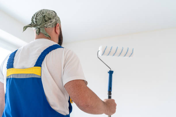 istock House painter with a paint roller in the empty white room ready for painting 2150282215