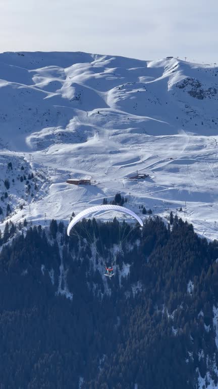 Paraglider over snowy mountains in French alps.