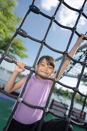 A girl is playing climbing and exercising at the playground.