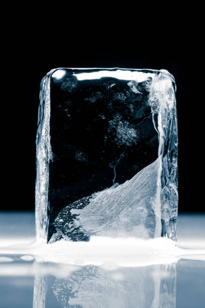 istock Crystal clear frosty textured natural ice block on a black background on a mirroring surface. 2150284604