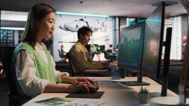 istock Asian Woman Using Desktop Computer And Designing In 3D Modelling Software Unique World And Characters For Survival Video Game In Diverse Office. Female Game Designer Creating Immersive Gameplay 2150284895