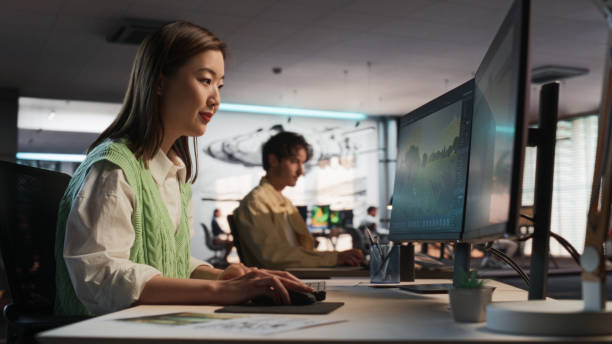 istock Asian Woman Using Desktop Computer And Designing In 3D Modelling Software Unique World And Characters For Survival Video Game In Diverse Office. Female Game Developer Creating Immersive Gameplay 2150284917
