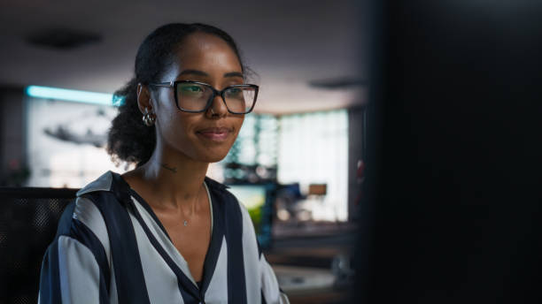 istock Black Woman Working on Desktop Computer in Creative Office. African American Marketing Manager Writing Email Messages, Developing Social Media Strategy, and Researching Project Plan Details Online 2150285038