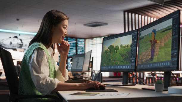 istock Female Asian Game Designer Using Desktop Computer, Designing Unique World And Characters In 3D modelling Software For RPG Video Game. Woman Working In Diverse Game Development Studio Office. 2150285535