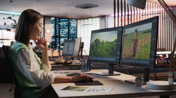 istock Female Asian Game Designer Using Desktop Computer, Designing Unique World And Characters In 3D modelling Software For RPG Video Game. Woman Working In Diverse Game Development Studio Office. 2150285549