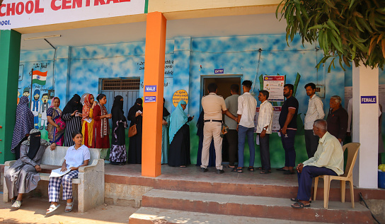 Mysuru, Karnataka, India-April 26 2024; A Group of People waiting in line to cast their Votes at a Polling station for the Indian Elections 2024 to elect the Prime Minister in Mysuru, India.