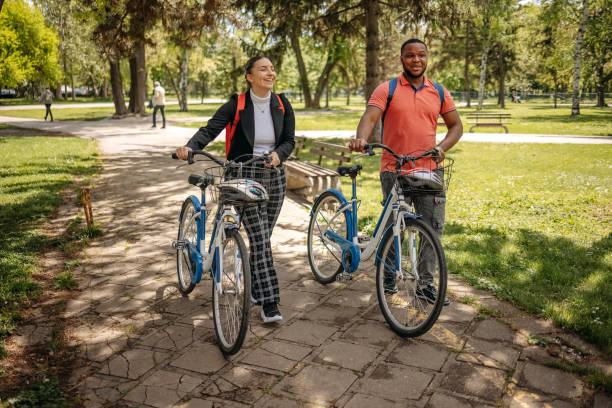 istock Two colleagues going to work walking through public park and pushing bikes 2150289913