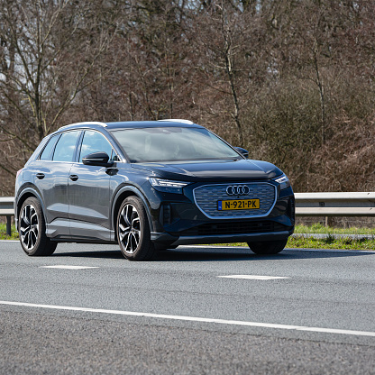 Netherlands, Overijssel, Twente, Wierden, March 19th 2023, side/front view close-up of a black 2021 electric Audi 1st generation Q4 e-tron SUV station wagon driving on the N36 at Wierden, the Q4 e-tron is made by German manufacturer Audi since 2021, the N36 is a 36 kilometer long highway from Wierden to Ommen