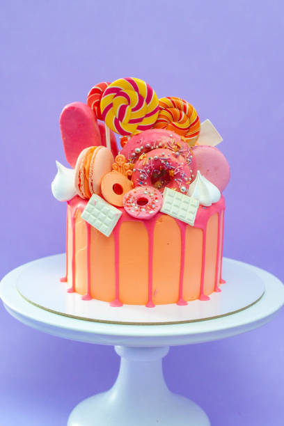 istock Tasty orange cake with sweets on plain purple background 2150289930