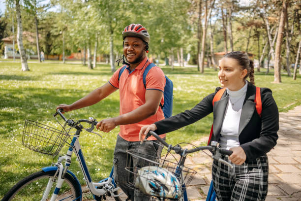 istock Two colleagues going to work walking through public park and pushing bikes 2150289957