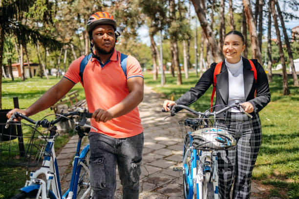 istock Two colleagues going to work walking through public park and pushing bikes 2150289975