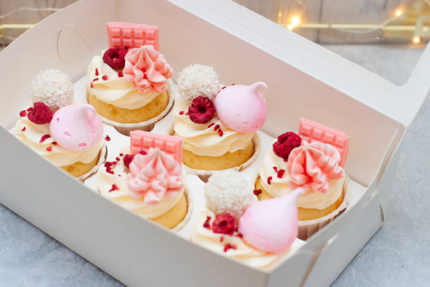 istock Gift box with beautiful pink cupcakes decorated with mini chocolate bars, meringue, raspberry and cream cheese frosting 2150294221