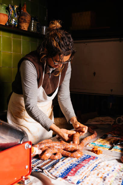 istock Focused female chef preparing linked sausage over table in kitchen 2150297140