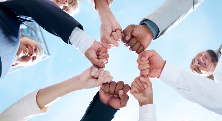 Teamwork, sky or business people with hands or fist for mission goals, collaboration or community. Team building, low angle or happy employees in meeting with support, solidarity or group motivation