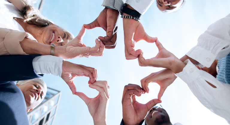 Love, support or business people with heart hands, care gesture or sky in community collaboration. Low angle, health or group of employees with teamwork, wellness symbol or thank you sign outdoors