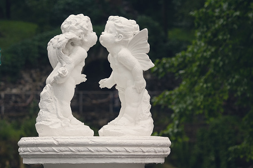 Angels leaning towards a kiss - a sculpture of white plaster standing in the park