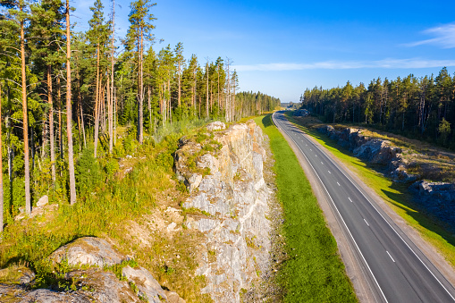 Karelia. Russia. The road goes beyond the horizon. Northern nature. Pine trees grow on the rocks. The highway is empty. Rest begins. Feeling of spaciousness. Fresh air.