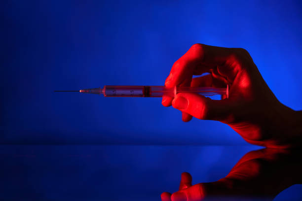 istock Unrecognizable person with syringe in neon lighting 2150305396