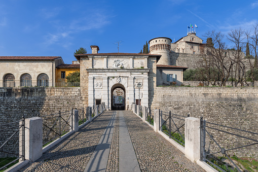 Brescia - Italy May 05, 2023: The main entrance to Brescia historical castle in Lombardy is adorned with a lion relief, leading visitors across a cobbled bridge to the fortified gates